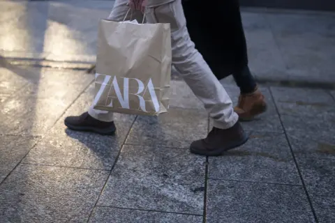Osoba idzie z torbą z logo ZARA. Może to być efekt zakupów zrobionych przez aplikację ZARA.