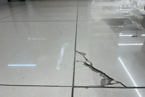 Baldosa rota en el suelo, con grietas y material desprendido. Una guía visual para saber como pegar una baldosa suelta.