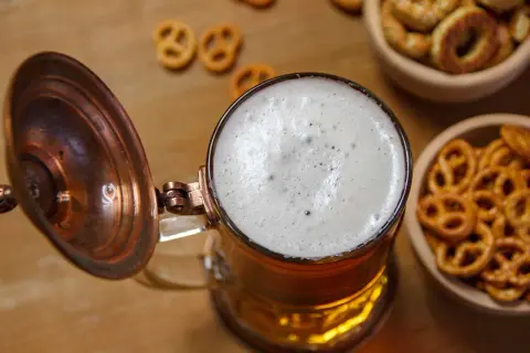 Piana na piwie w kuflu, obok miseczki z precelkami. Zastanawiasz się, ile kcal ma piwo?