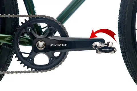 Czerwona strzałka pokazuje kierunek obrotu, by dowiedzieć się, jak odkręcić pedały w rowerze. Widoczny mechanizm korbowy Shimano GRX.