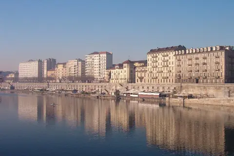 I **murazzi** di Torino si specchiano nel fiume, con palazzi storici e moderni che si affacciano sulla riva.