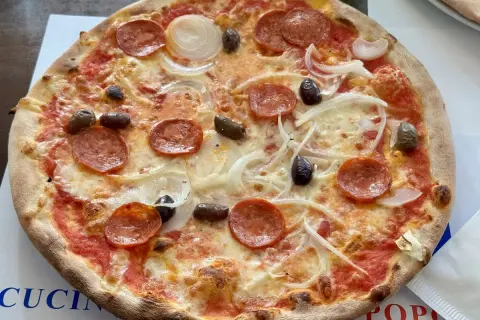 Eine köstliche Pizza mit Salami, Zwiebeln und Oliven, frisch aus i due forni.