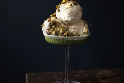 Krämig pistageglass i ett elegant glas, toppad med krossade pistagenötter. Ett perfekt pistageglass recept för en lyxig dessert.