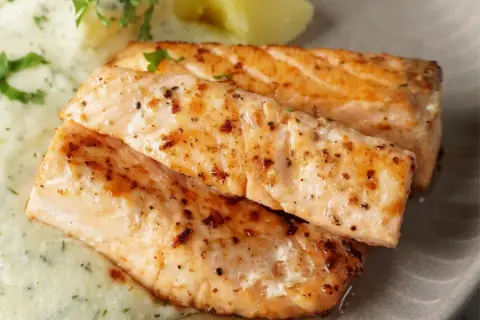 Zwei saftige Lachsfilets, perfekt gebraten, mit cremiger Sauce und Kartoffeln. Ein tolles Gericht für Lachs Rezepte.