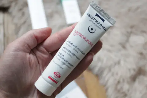 Crème anti-rougeurs pour la rosacée, contenant de l'acide azélaïque. Le tube Metroruboril A.Z d'Isispharma est tenu dans une main.