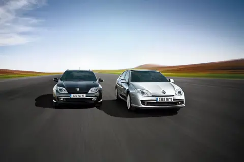 Dwa modele Renault Laguna 3, czarny i srebrny, pędzą po pustej drodze na tle rozmytego krajobrazu.