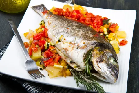 Dorada a la espalda, horneada con verduras y hierbas frescas, lista para disfrutar.