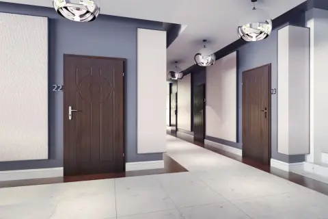 Nowoczesny korytarz w bloku z drzwiami, które można wyciszyć. Jasne panele i kule lamp dodają elegancji.