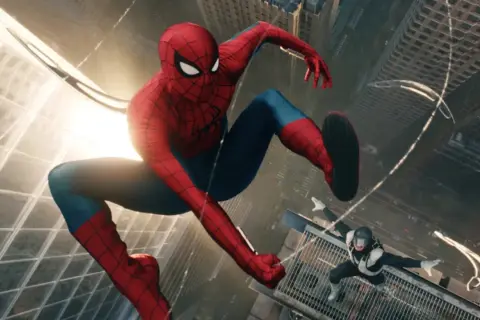 Spiderman w swoim ikonicznym stroju skacze między wieżowcami. Na dole inny przeciwnik w czarno-białym stroju.