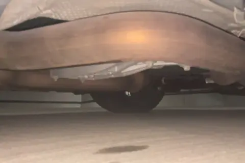 Mörk fläck på marken under bilen, troligen olja. Avgassystemet syns tydligt.