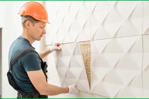 Obrero coloca paneles 3D blancos, una solución moderna para forrar una pared con humedad.