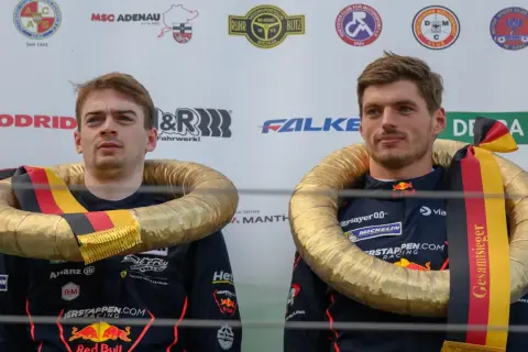 Max Verstappen celebra su victoria en el Nürburgring con un collar dorado y la bandera alemana.