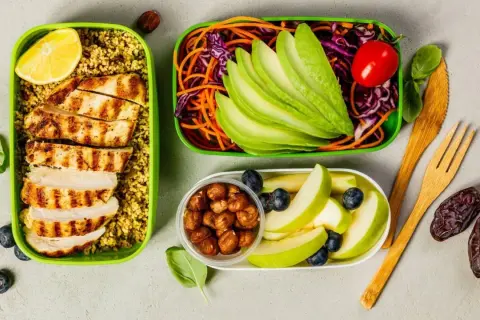 Gesunde gerichte zum vorkochen: gegrilltes Hähnchen mit Couscous, Avocado-Salat, Äpfel und Nüsse.