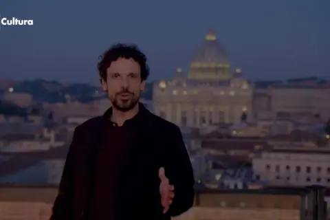 Francesco Montanari, con la sua altezza, parla davanti a San Pietro al tramonto.