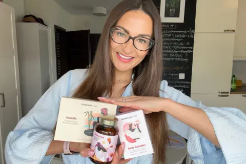 Kobieta z okularami prezentuje suplementy Health Labs Care, które pomagają w walce z niską ferrytyną i poprawiają kondycję skóry.