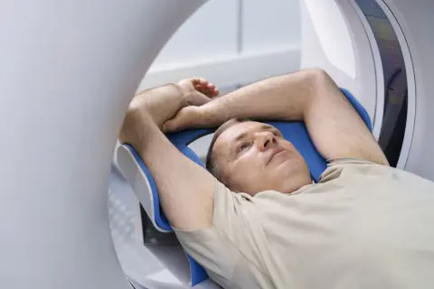 Mężczyzna leży w rezonansie magnetycznym. Zastanawia się, czy przed rezonansem można jeść.