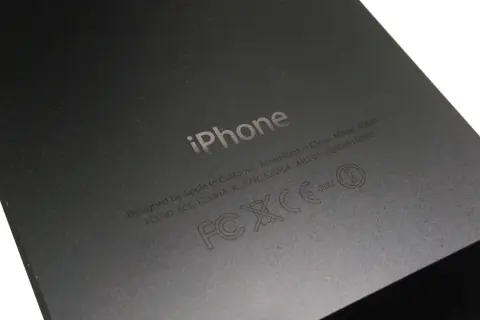 Tył iPhone'a z wygrawerowanym logo i informacjami, w tym numerem IMEI: 013408009192055.
