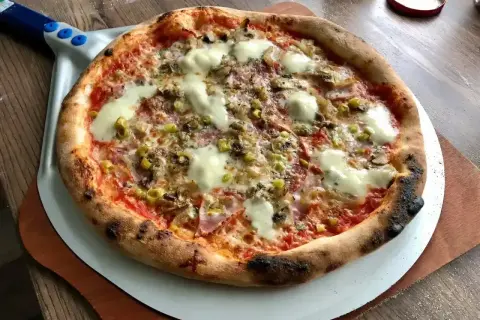 Gorąca pizza salami z roztopionym serem, oliwkami i pieczarkami, gotowa do podania.
