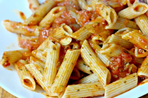 Pyszny makaron penne z aromatycznym sosem pomidorowym, posypany ziołami. Idealny na szybki obiad.