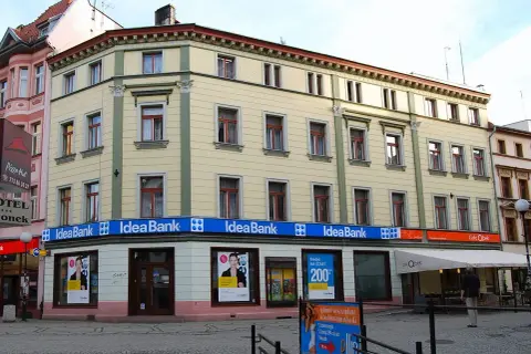 Elegancki budynek z szyldami Idea Bank i Cafe Qbek. W witrynach banku reklamy kredytów i usług.