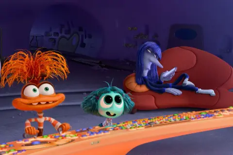 Hier ist alles steht kopf 2 emotionen: Ein orangefarbenes Wesen mit struppigen Haaren drückt Knöpfe, ein kleines blaues Wesen schaut neugierig, während ein langes, blaues Wesen auf einer Couch liegt und auf sein Handy schaut.