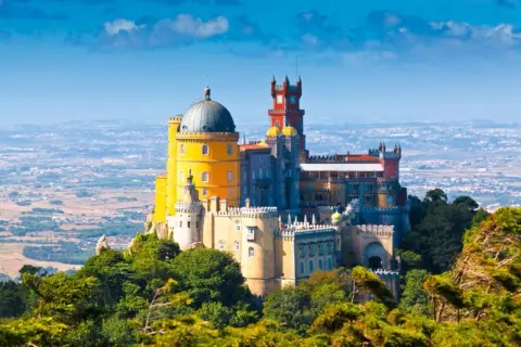 El Pazo da Pena, un palacio de cuento de hadas con cúpulas y torres coloridas, se alza majestuoso sobre una colina verde.