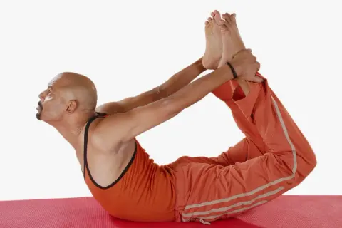 Hombre en postura del arco yoga, estirando su espalda y piernas.