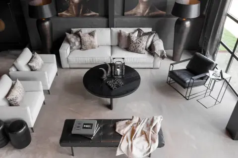 En modern lounge med soffa, fåtöljer och ett runt soffbord. En stilren och maskulin inredning med fokus på mörka toner och geometriska former.