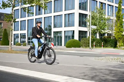 Mann fährt mit E-Bike durch eine moderne Stadt in Deutschland.