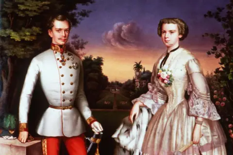 Sissi et Maximilien, frère de Franz, posent dans un jardin. Elle porte une robe élégante, lui un uniforme militaire.