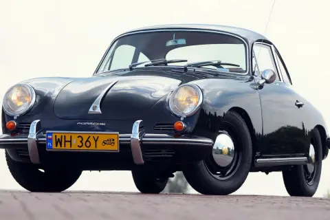 Czarne, zabytkowe auto Porsche z lat 50. XX wieku, z charakterystycznym przodem i żółtą tablicą rejestracyjną.