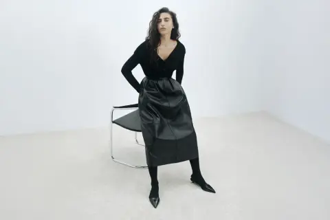 Elegancka czarna spódnica z ekoskóry, zestawiona z czarnym swetrem i butami. Stylowe czarna spódnica stylizacje.