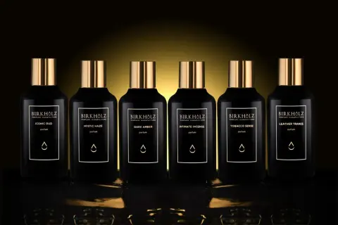 Sześć czarnych flakonów perfum Birkholz z złotymi nakrętkami. Jeden z nich to "Dark Amber", o głębokim, **dark amber** kolorze.