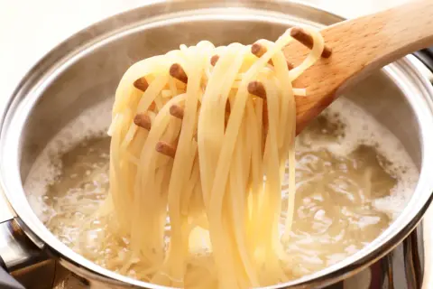 Spaghetti fraîchement cuits à l'italienne, retirés d'une casserole d'eau bouillante avec une cuillère en bois.