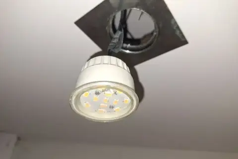 Oprawa natynkowa GU10 z widoczną żarówką LED, zamontowana na suficie.