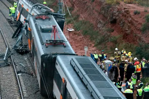 Olycksplats med ett urspårat tåg i Spanien. Räddningspersonal undersöker vraket.