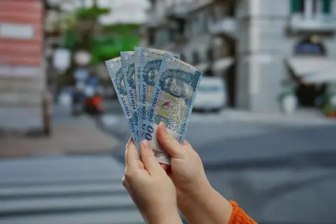 Dłonie trzymają banknoty po 1000 forintów. Sprawdzanie cen na Węgrzech.