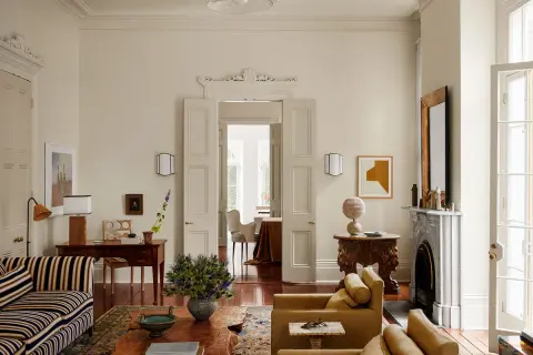 Soggiorno elegante con divani color ocra e un raffinato abbinamento colori crema. Tavolino in legno grezzo e tappeto decorato.