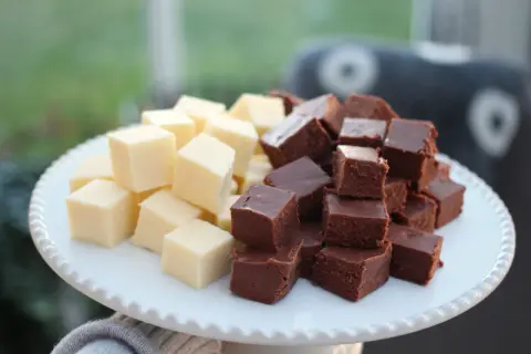 En vit bricka med staplade bitar av ljus och mörk fudge. Perfekt för ett enkelt fudge recept.