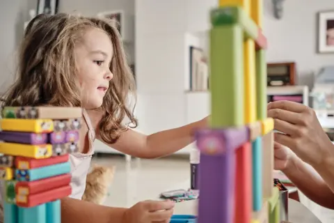 Niña concentrada construyendo con bloques de colores, disfrutando de juegos de habilidad para niños.