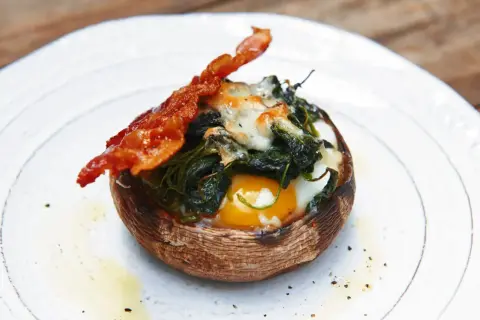 Gefüllter Portobello Pilz mit Ei, Spinat und Käse, garniert mit knusprigem Speck. Ein einfaches und leckeres Portobello Pilz Rezept.