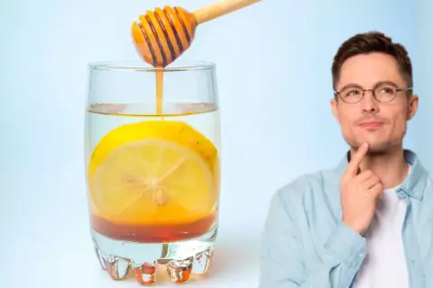 Hombre pensativo junto a un vaso de agua con limón y miel, perfecto para empezar el día.
