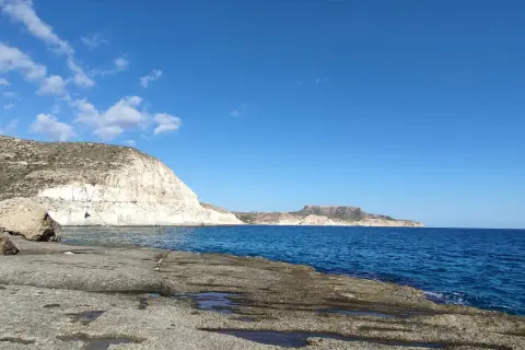 Costa rocosa y mar azul en la cala cortada Almería. El sol ilumina las formaciones rocosas y el agua cristalina.