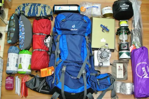 Alles, was man braucht für Camping: Rucksack, Schlafsäcke, Isomatten, Kocher, Lampe, Zeltstangen, Tasse und mehr.