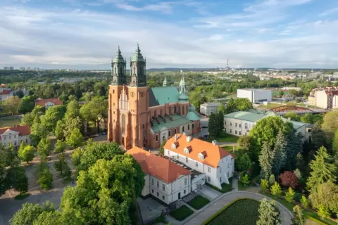 Widok na Ostrów Tumski z dominującą katedrą. Wokół zieleń drzew i zabudowania miejskie.