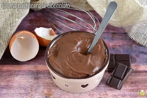 Crema pasticcera al cioccolato, liscia e invitante, pronta per essere gustata. Uova, frusta e cioccolato, ingredienti per un dolce momento.