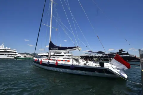 Barca a vela "Nababbo" con bandiera rossa e bianca, in porto con altre imbarcazioni. Sembra una cometa 12.