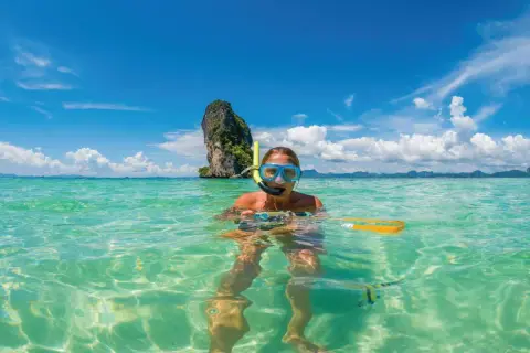 Kobieta w masce do snorkelingu pływa w turkusowej wodzie. Czy Tajlandia jest bezpieczna? Tak, to raj dla turystów!