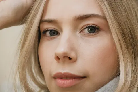 Zbliżenie na twarz młodej kobiety z blond włosami. Zastanawiasz się, ile rzęs wypada dziennie?