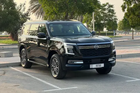 Czarny Nissan Patrol 2025 zaparkowany na tle drzew i palmy.